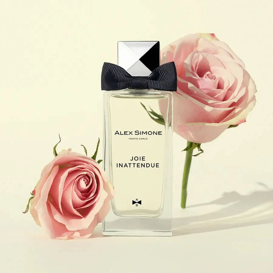 Perfumy niszowe Joie Inattendue flakon z czarną kokardą i różami w tle